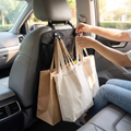 Person hanging bags on the car headrest hooks, off the floor