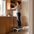 Person standing safely on a folding step stool to reach a high cupboard