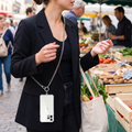 Person wearing phone hands-free on a crossbody lanyard strap at a market