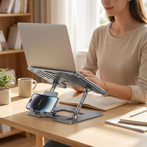 Person working upright at a desk with laptop raised on the adjustable steel stand