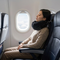 Traveller asleep in a plane seat supported by the memory foam neck pillow